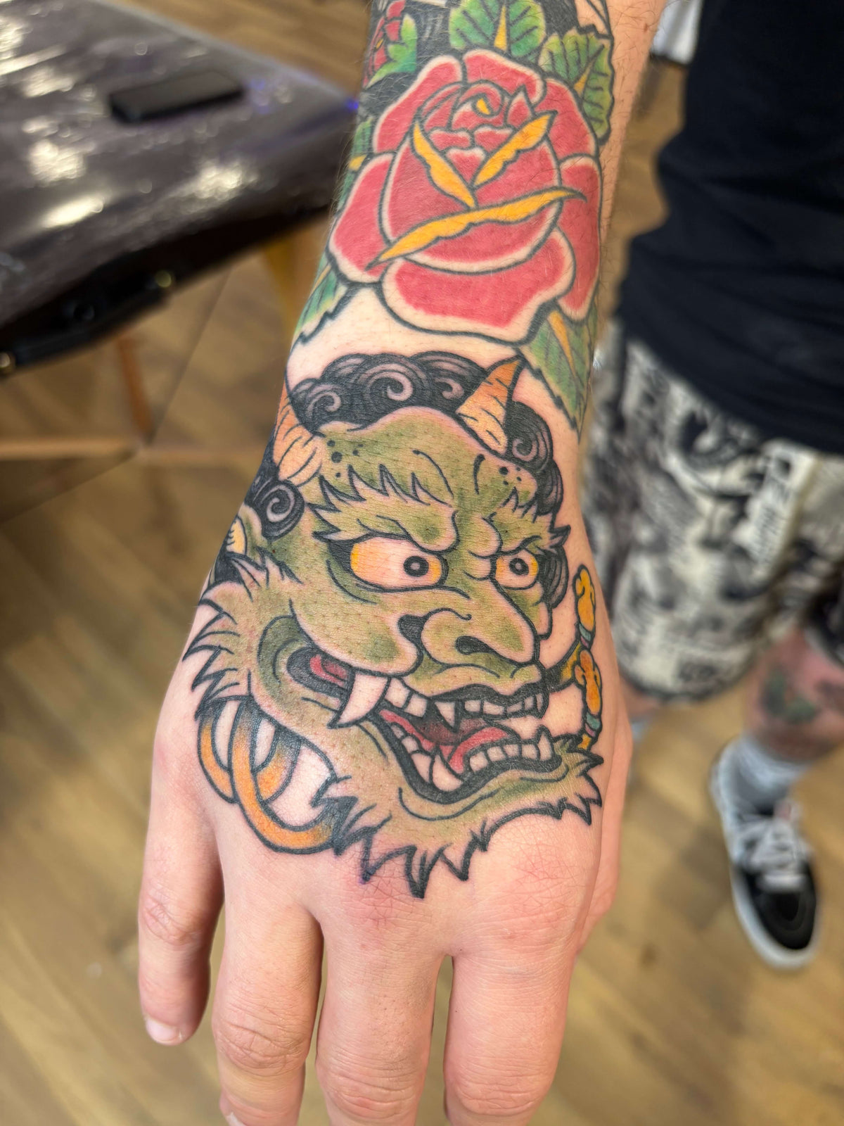 japanese oni mask tattoo on a hand with a traditional rose 
delboitattoos