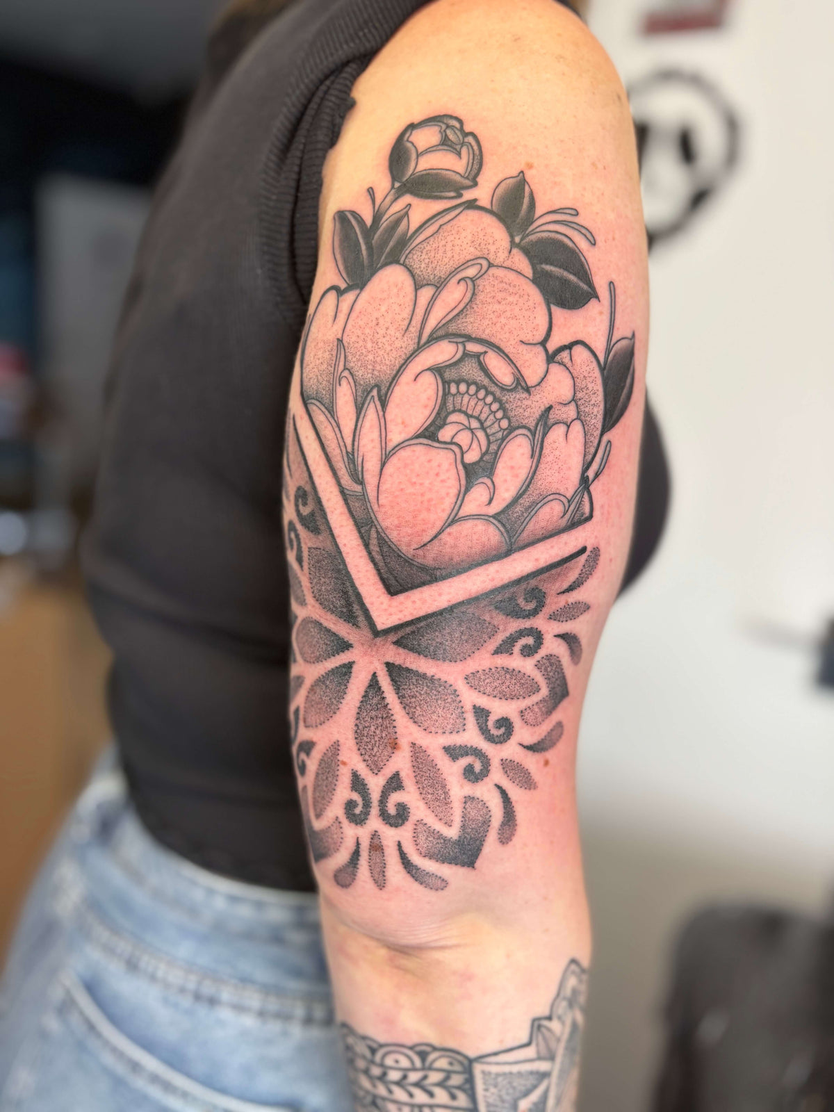blackwork style peony flower with a dot work mandala tattoo on the arm
delboitattoos
