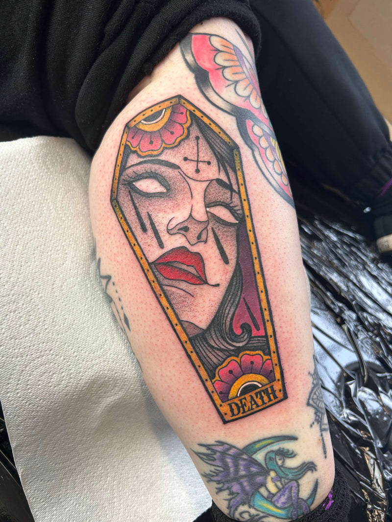 coffin shaped colour tattoo with woman's face in a Neo traditional style with death in script
delboitattoos